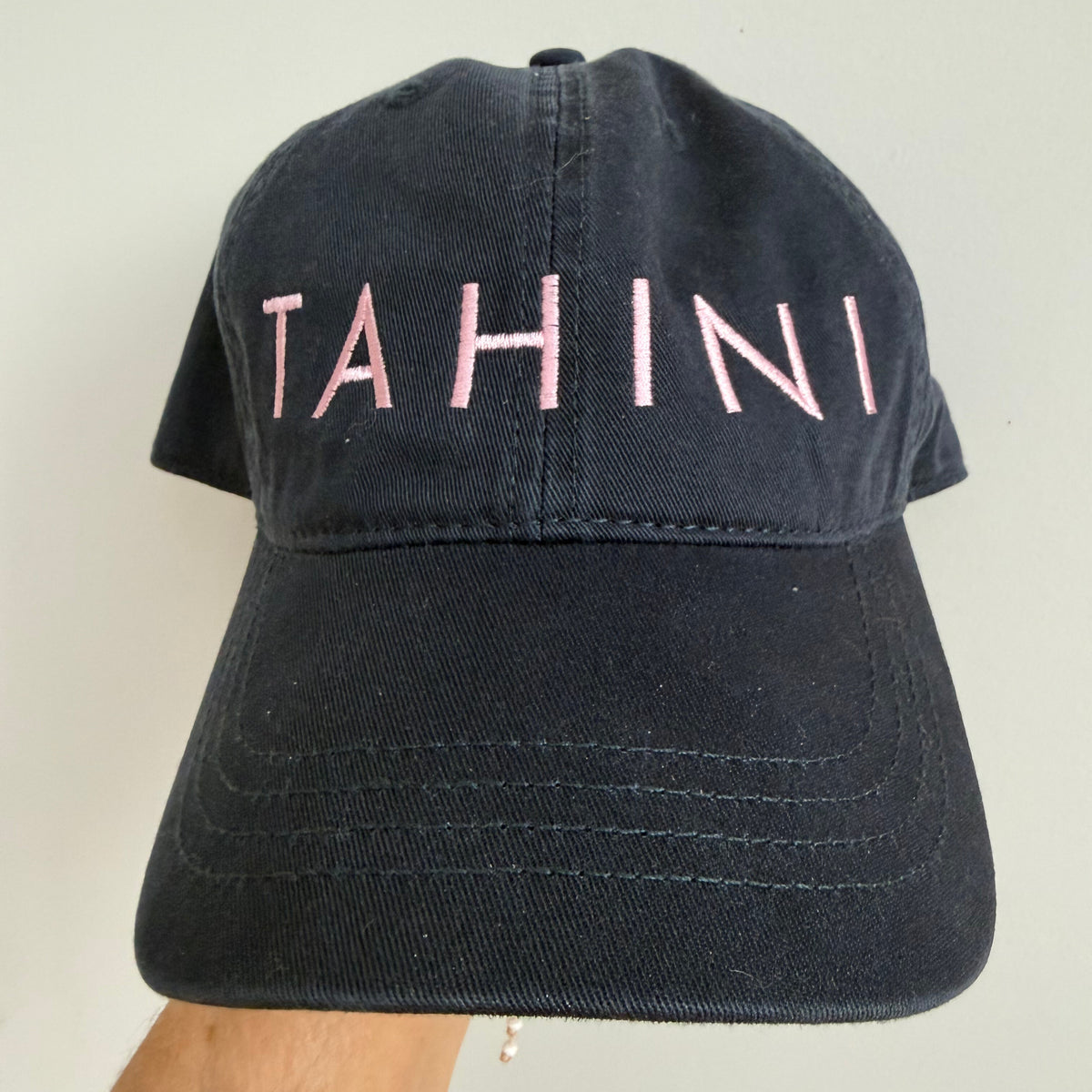 Navy blue baseball hat with TAHINI in light pink thread 