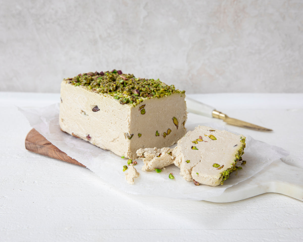 Halva loaf with pistachios on a white surface