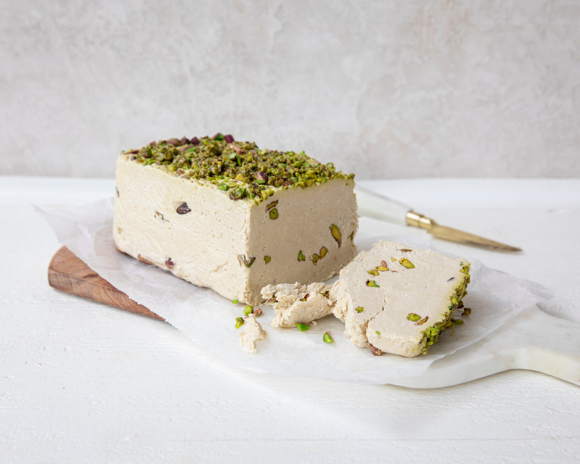 Halva loaf with pistachios on a white surface