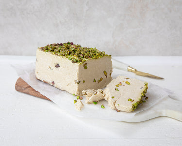 Halva loaf with pistachios on a white surface