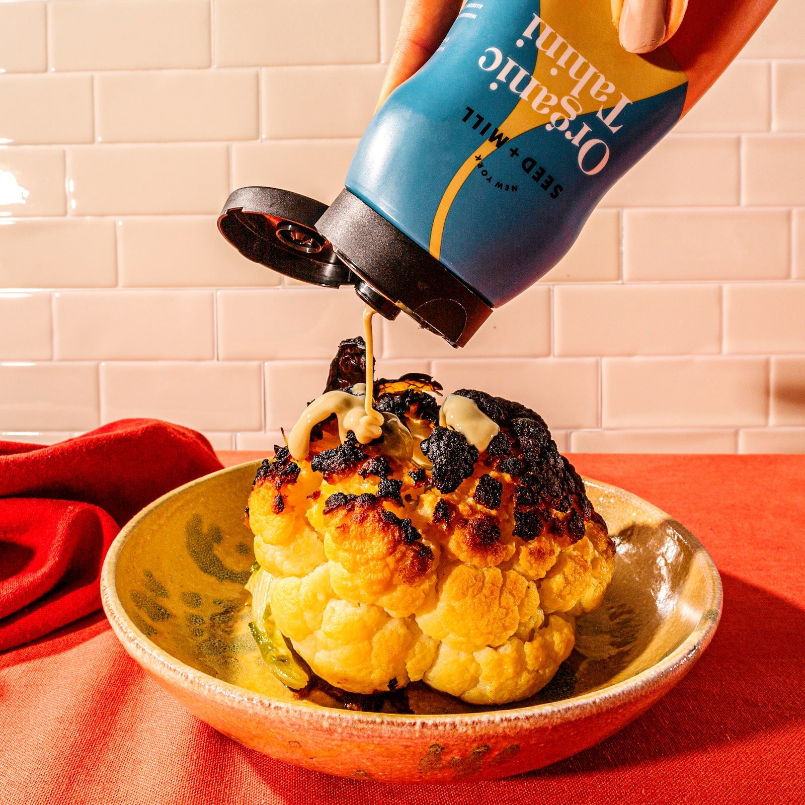A plate of roasted cauliflower with Organic Tahini being squeezed on top