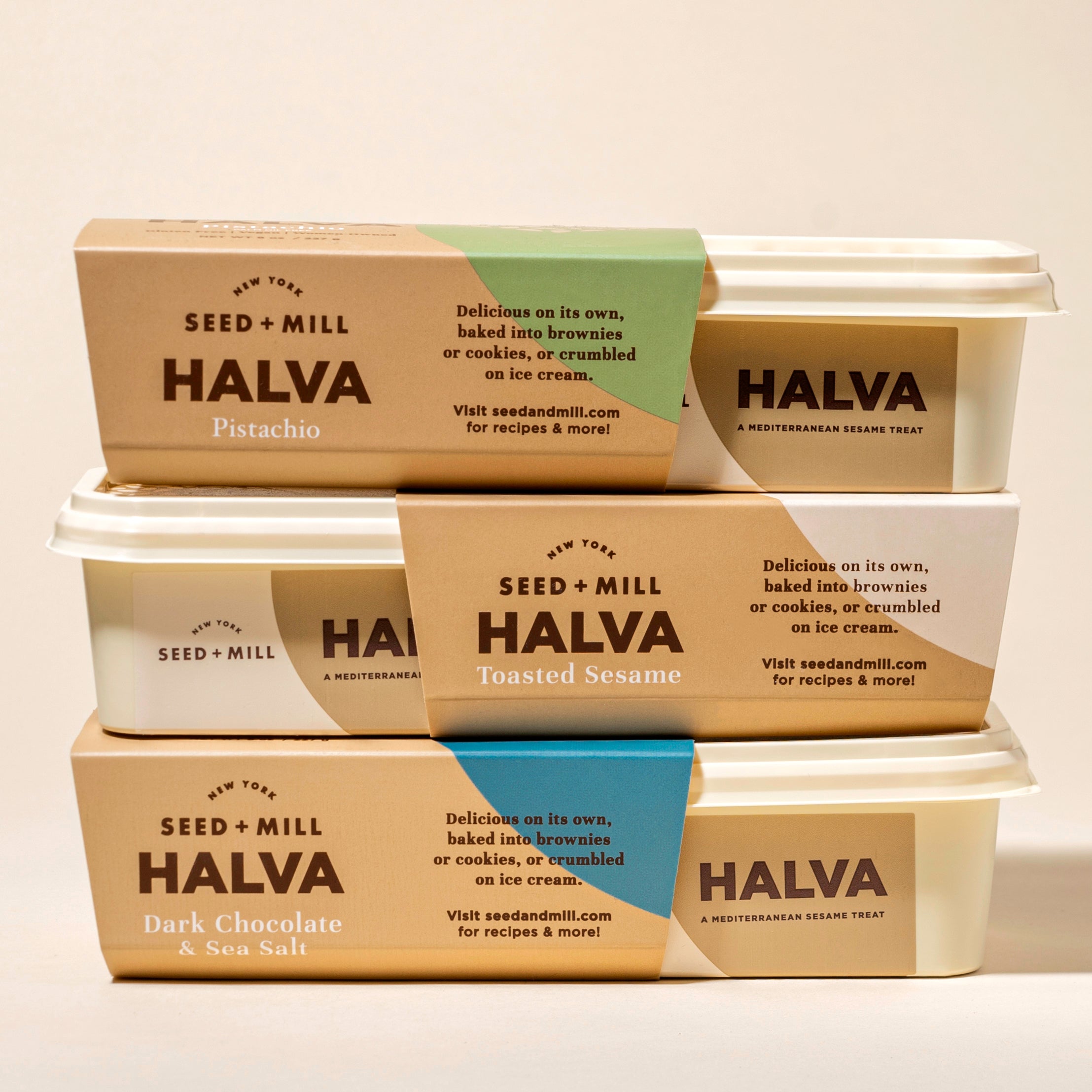 Stack of Seed + Mill Halva containers with different flavors on a white background