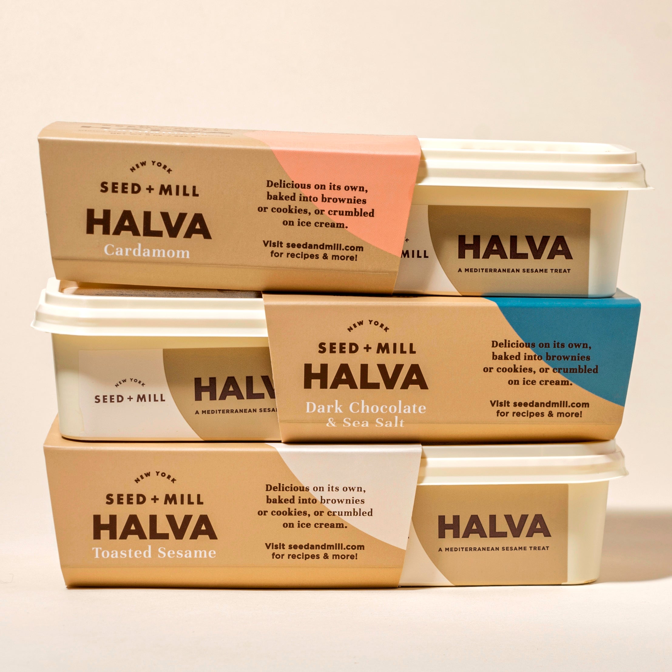Stack of Seed + Mill Halva containers on a beige background