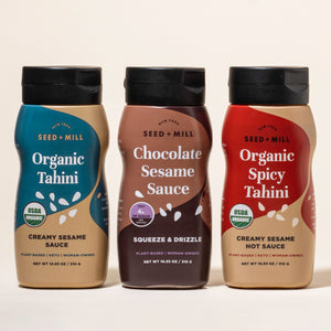 Three bottles of Seed + Mill Tahini, Organic Spocy Tahini, Chocolate Sesame Sauce, and Organic Tahini, on a beige background