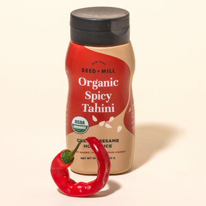 Squeeze bottle of Organic Spicy Tahini with a red chili pepper on a white background
