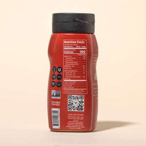 Back of a squeeze bottle of Seed + Mill spicy tahini with nutrition facts label on a beige background